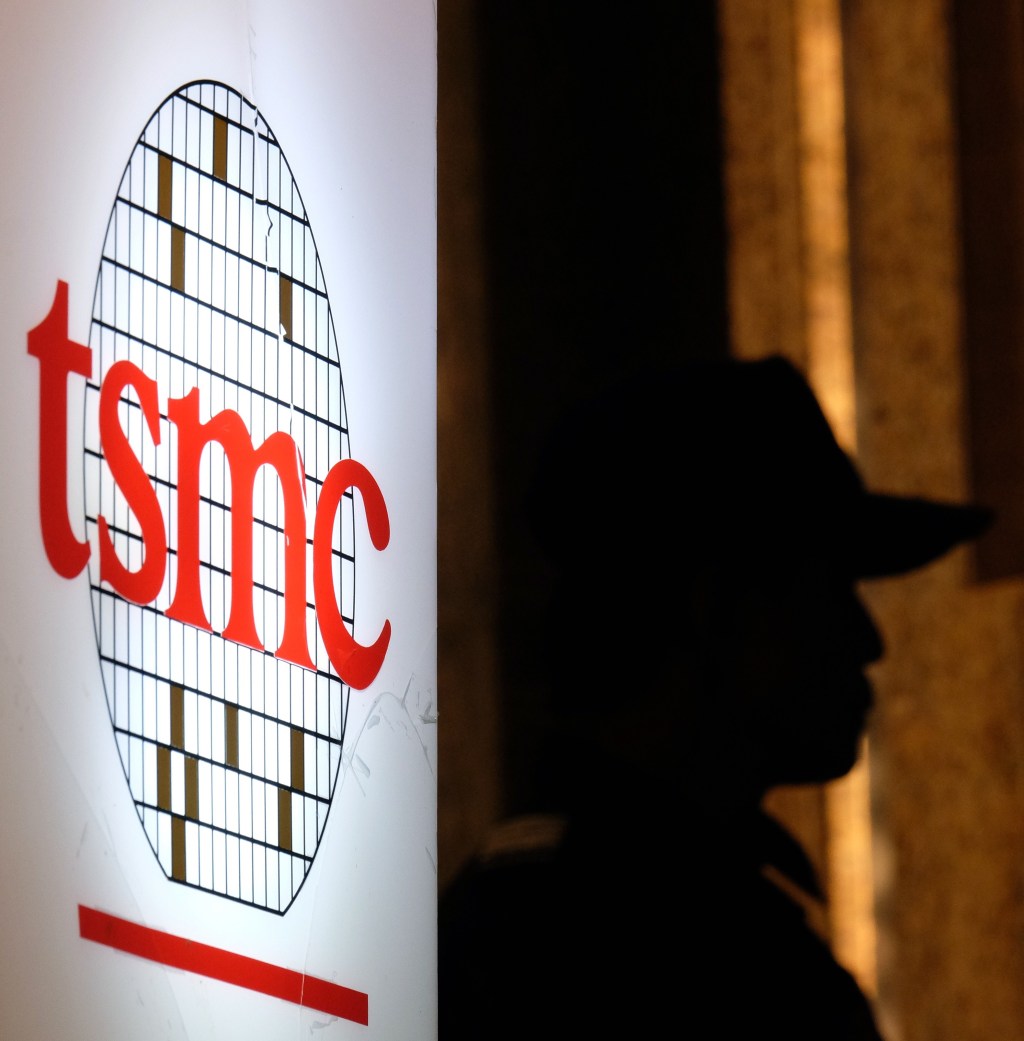 A security staff stands next to a logo of the Taiwan Semiconductor Manufacturing Co, (TSMC), during the investors conference in Taipei on July 16, 2014.