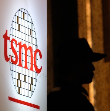 A security staff stands next to a logo of the Taiwan Semiconductor Manufacturing Co, (TSMC), during the investors conference in Taipei on July 16, 2014.