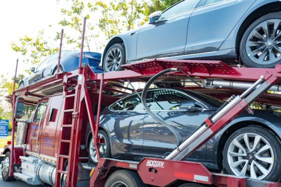 Brand new Tesla electric cars, including the Tesla Model 3 on a car carrier truck awaiting delivery.