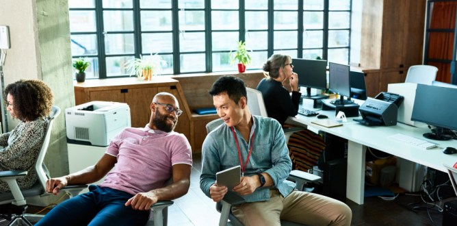Two men chatting in office with digital tablet