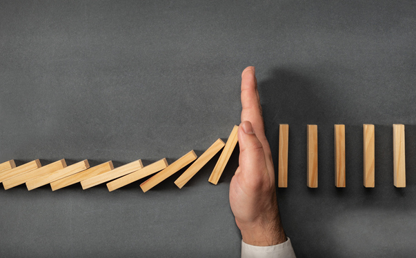 Chain Reaction In Business Concept, Businessman Intervening Dominoes Toppling; cut spending