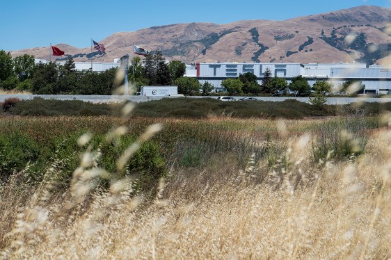 Tesla factory in the distance of a field of wheat