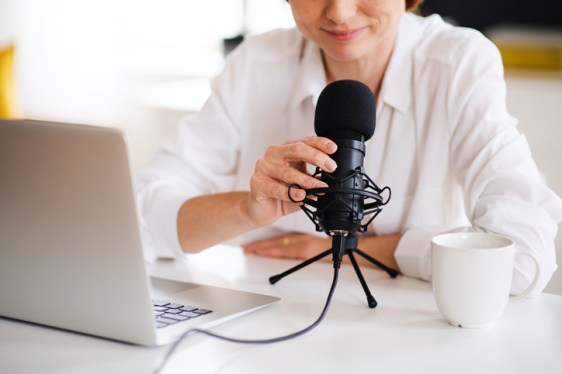Woman vlogger or blogger seated with laptop and microphone.