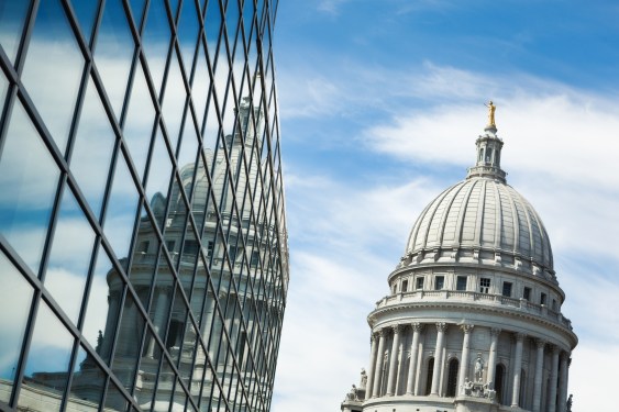 Image of a government building reflected in a glass office building to represent public-private partnership.