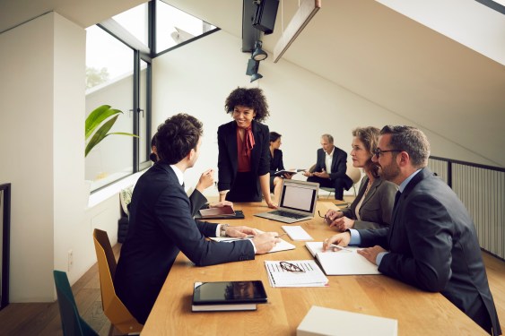 A group of lawyers working at a conference table with laptops and tablets