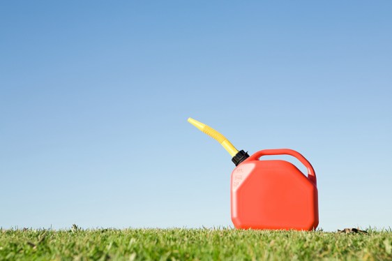 A red gas can sitting on grass under a blue sky