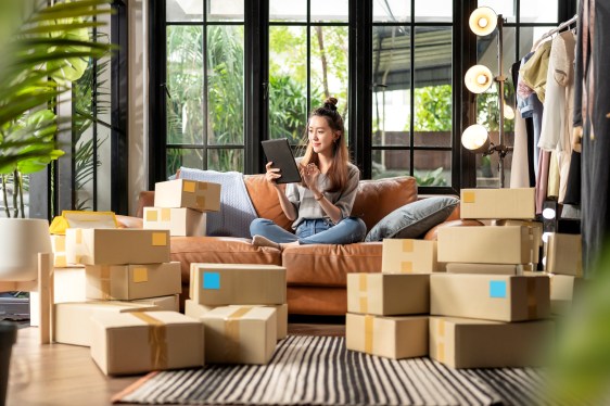 Woman talking on phone, sitting on couch, surrounded by shipping boxes