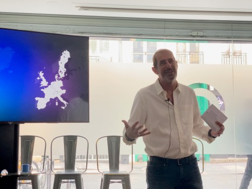 man talking in front of large video board