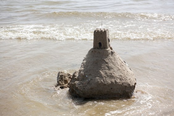 Sandcastle being slowly washed away at Littlehampton beach, West Sussex