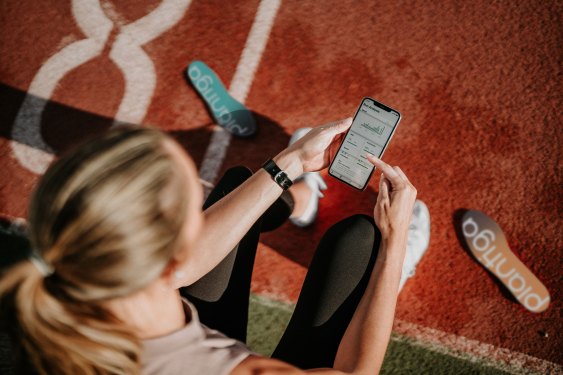 woman at track checking running shoes