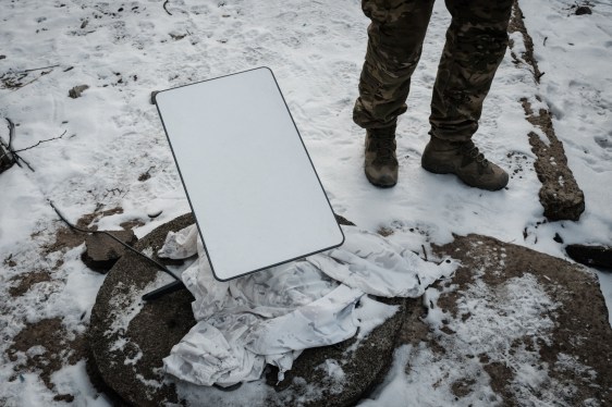 A Ukrainian serviceman stands next to the antenna of the Starlink satellite-based broadband system in Bakhmu.
