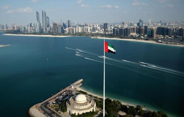 UAE flag flying in front of ocean/skyline