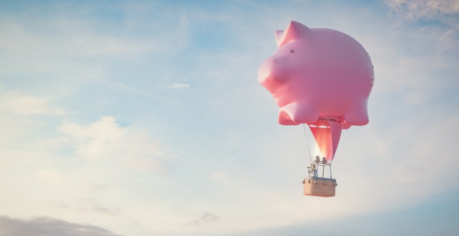 A pink piggy bank as a hot air balloon