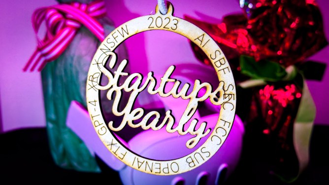 A laser cut bauble reading "Startups Yearly 2023" with the text AI, SBF, SEC, FCC, SUB, OPENAI, FTX, GPT-4, XR, R and NSFW on it