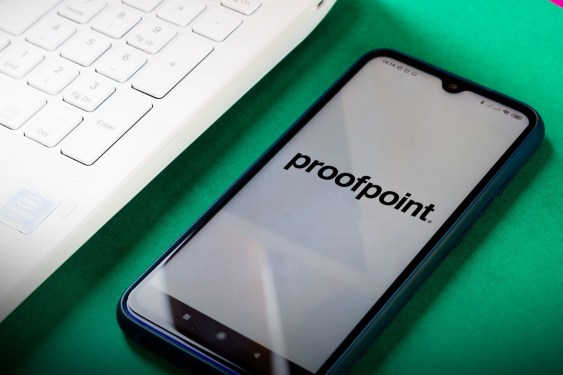 proofpoint logo on a phone next to a laptop on a green desk