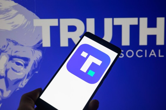 The Truth Social app icon is being displayed on a smartphone with Truth Social visible in the background in this photo illustration.