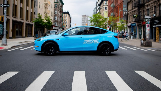 Light blue Revel rideshare mid-street