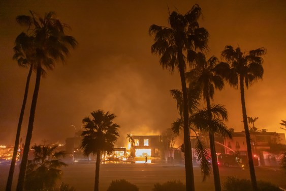 A firefighter watches the flames from the Palisades Fire burning homes on the Pacific Coast Highway amid a powerful windstorm on January 8, 2025 in Los Angeles, California.