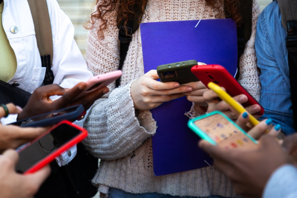 Close up of young college students hands holding mobile phones.