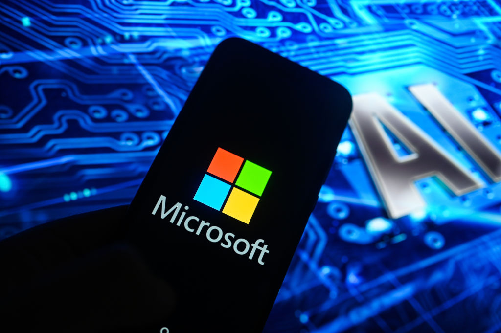 Image of a smart phone with the Microsoft logo on it with "AI" in the background