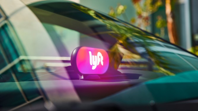 A lighted Lyft sign on a car's dash.