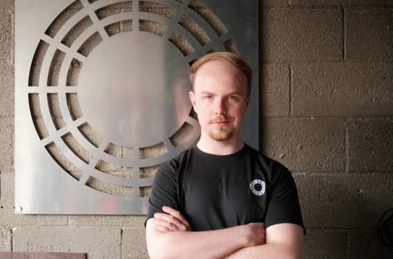 Durin founder Ted Feldmann stands before metal art.