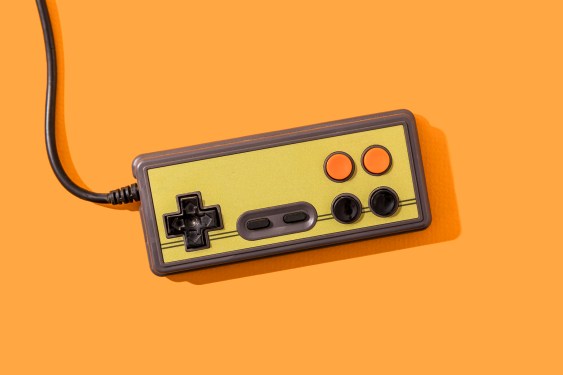 Retro video game controller on orange background.