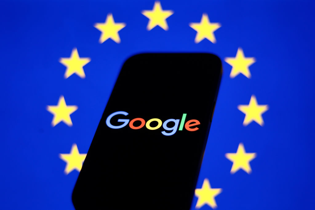 European Union flag displayed on a laptop screen and Google logo displayed on a phone in front of it