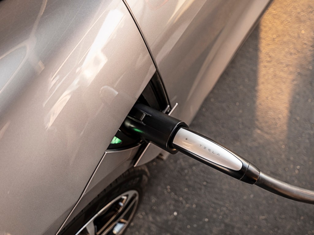 A close up image showing a Tesla charger is plugged into a Lucid Air sedan.