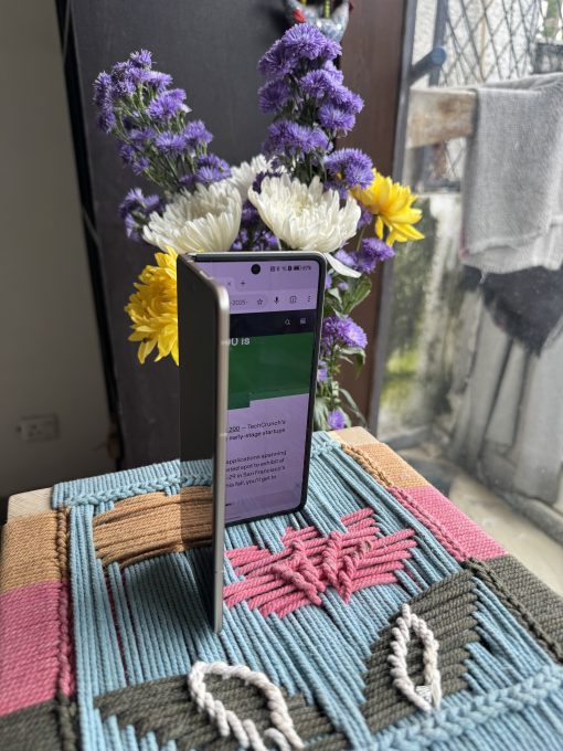 A photo showing Honor Magic V5 half unfolded with TechCrunch's site open.