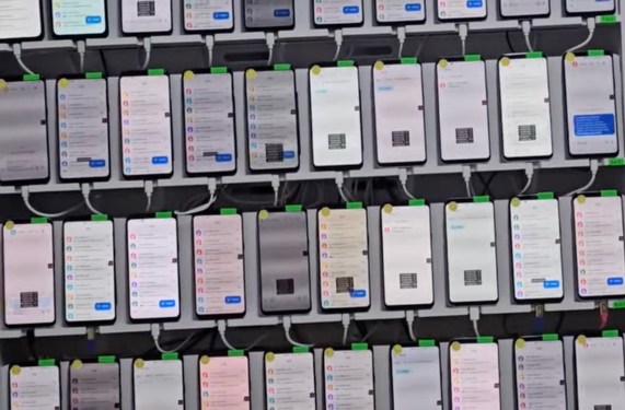 a photo showing a rack containing dozens of smartphones mounted and being used to automate scam messages. the photo was found in a Telegram group used by the scammers.