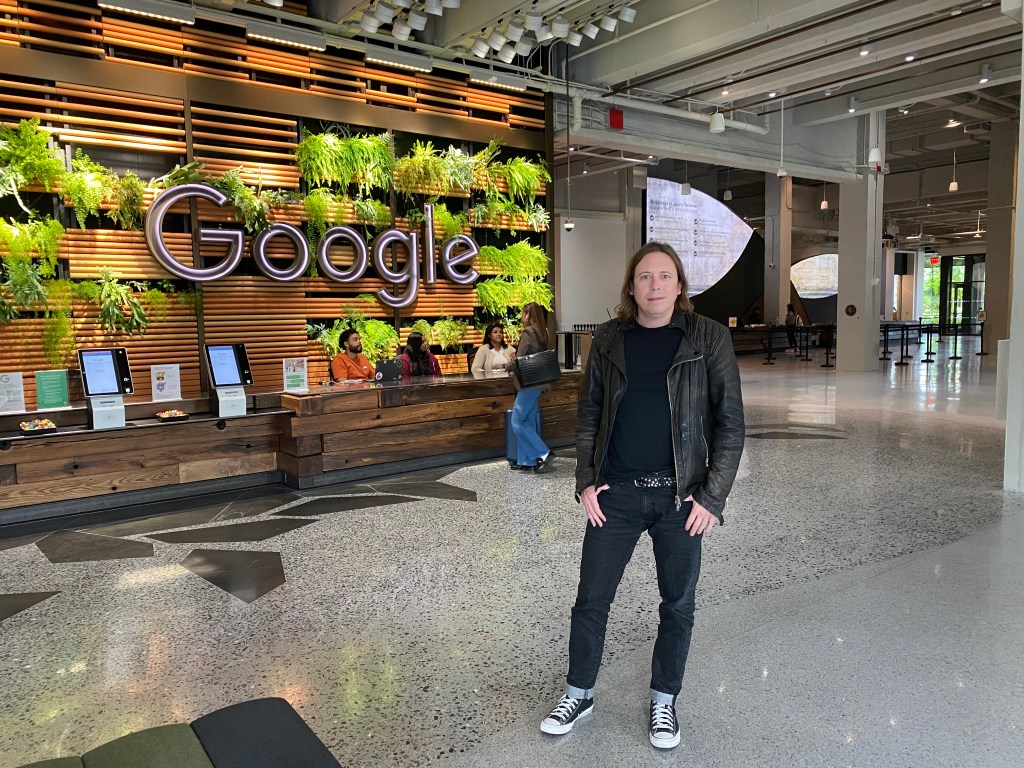 Ryan Salvo, wearing a black leather jacket, stands in the lobby of a Google office.