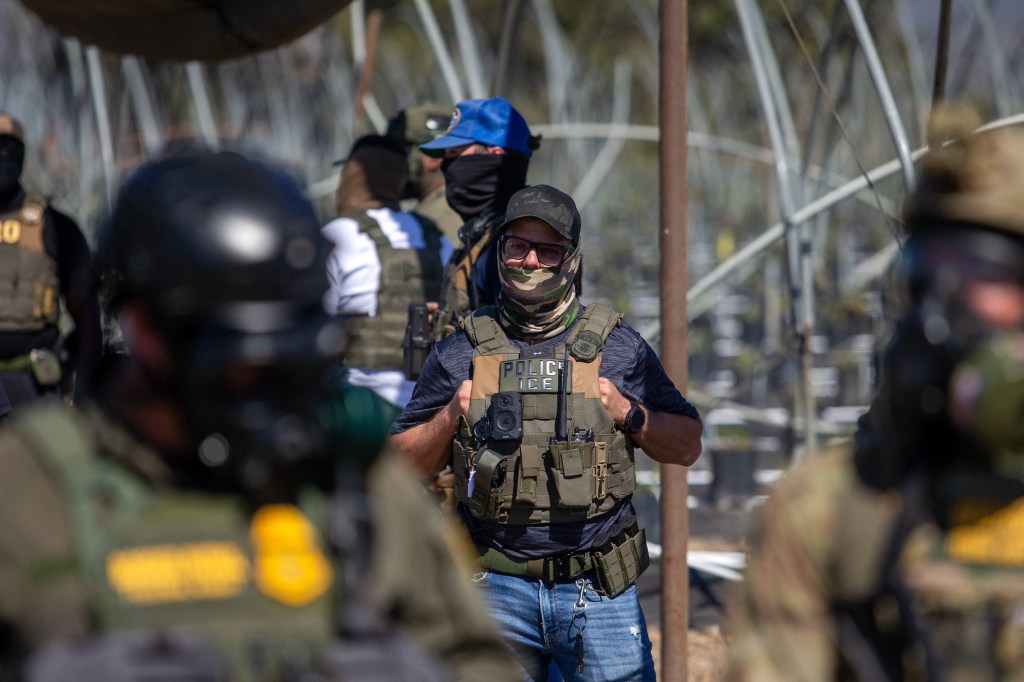 A US Immigration and Customs Enforcement agent watches as Customs and Border Protection officers hold the line against protestors who responded to a Federal Immigration raid at Glass House Farms in Camarillo, California, July 10, 2025.