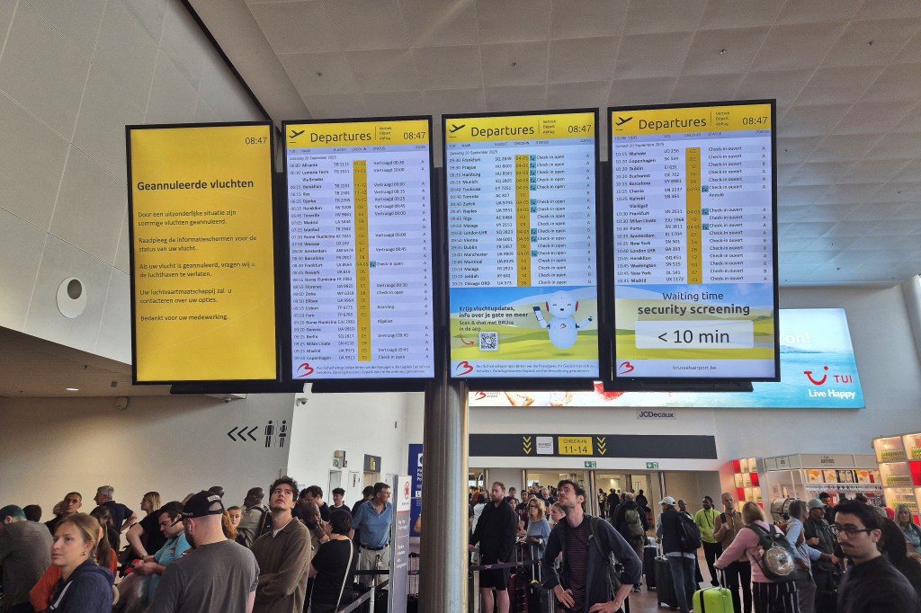 This photograph shows passengers waiting next to a flight information board of the Brussels Airport in Brussels on September 20, 2025, after the airport's system was hit by a "cyberattack" overnight on September 19.