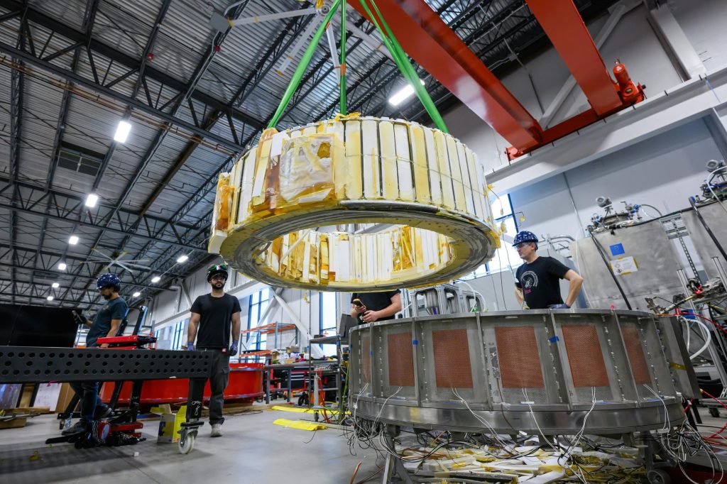 Engineers watch as a magnet is moved inside Commonwealth Fusion System's building.