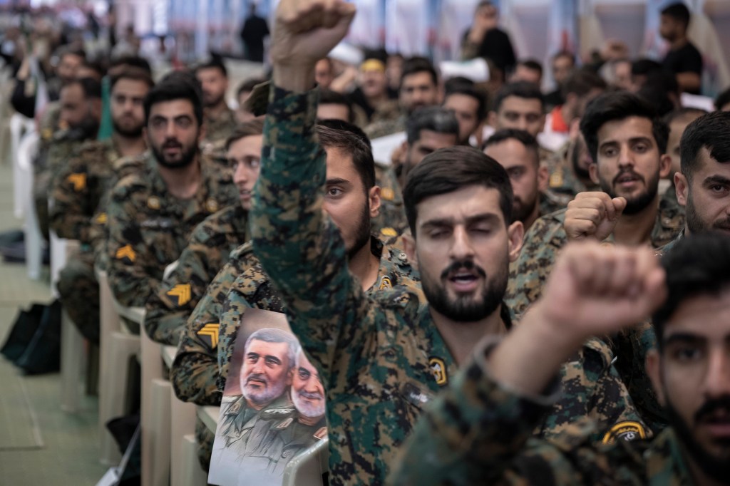 Military members of the Iranian police special forces shout anti-U.S. and anti-Israeli slogans as one of them holds a poster featuring portraits of the former commander of the Islamic Revolutionary Guard Corps Quds Force, Major General Qassem Soleimani, who is killed in a U.S. strike in Baghdad, and Brigadier-General Amir Ali Hajizadeh, former Commander of the IRGC - Aerospace Force, during a ceremony at the Imam Khomeini Grand Mosque in Tehran, Iran, on August 7, 2025, to commemorate the civilians and Islamic Revolutionary Guard Corps (IRGC) generals killed during the 12-day war between Iran and Israel.