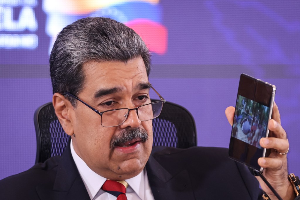 President of Venezuela Nicolás Maduro shows his cell phone during a press conference