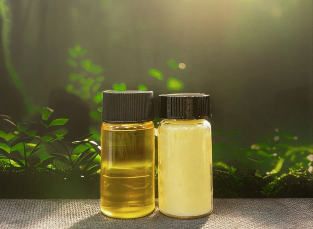 Two vials of oil sit against a leafy backdrop.