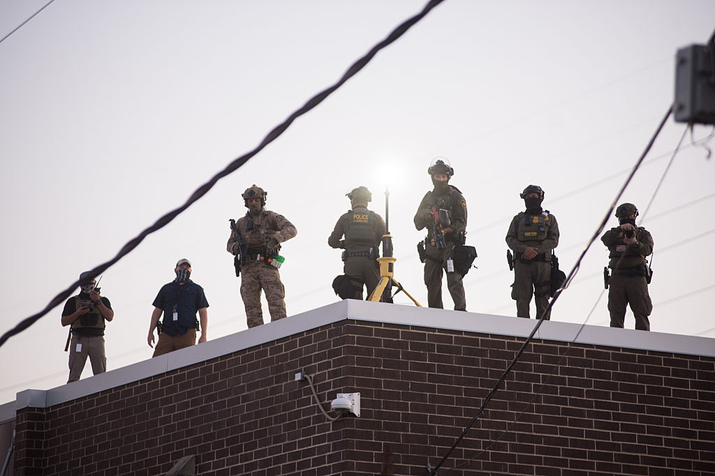 U.S. Immigration and Customs Enforcement (ICE) agents, Department of Homeland Security (DHS) personnel, and Border Patrol Commander Gregory Bovino stand together amidst a tense protest outside the ICE processing facility in Broadview, Illinois, on September 27, 2025.